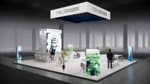 Beursstand Een moderne beursstand voor TBU Technisch Bureau Uittenbogaart, met beeldschermen, planten, een ontvangstruimte, zitplaatsen en interactie tussen bezoekers in een ruime, goed verlichte beursruimte.