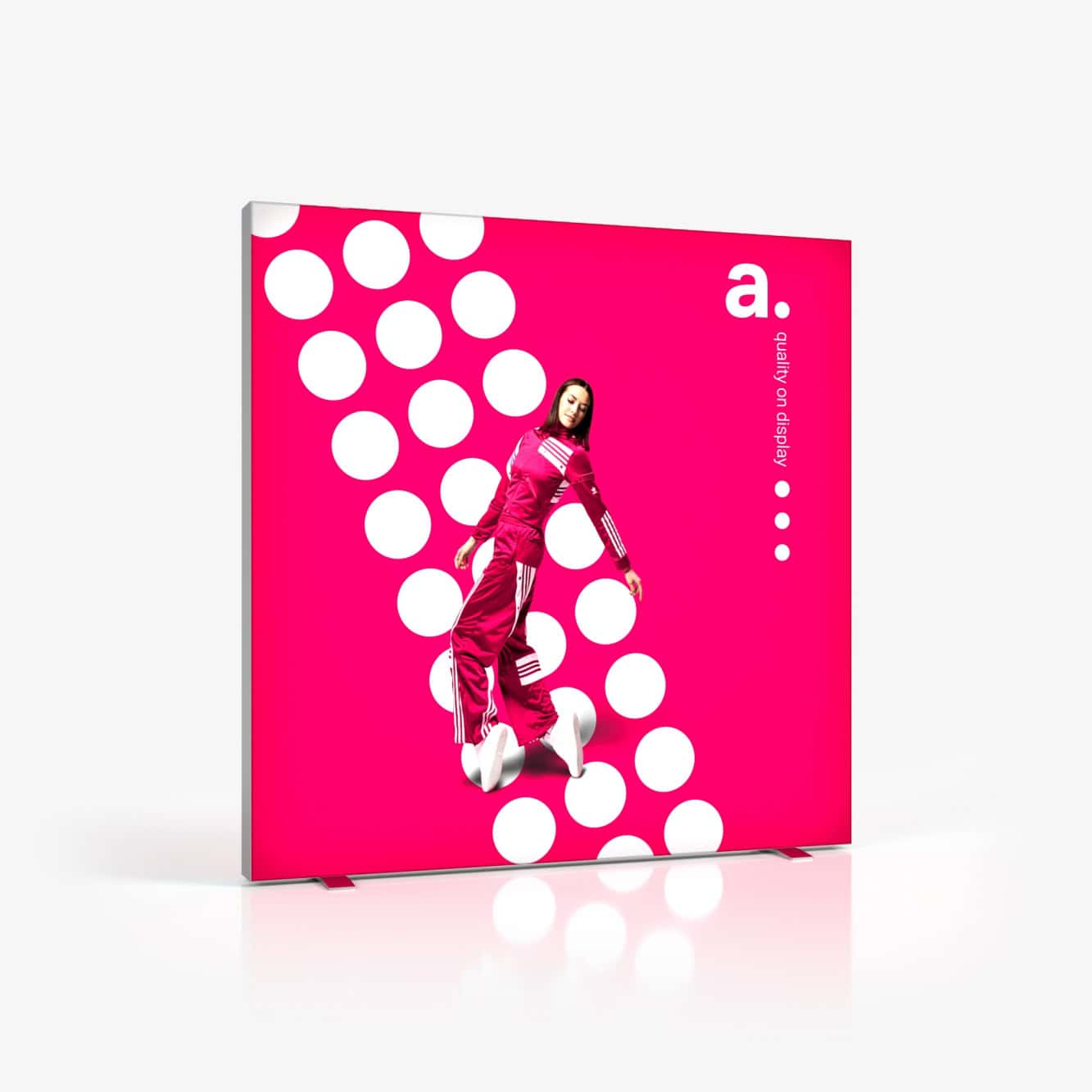 Beursstand Een persoon in een roze trainingspak poseert energiek voor de Portable LED LMD - 150x250cm (kopie), met een felroze achtergrond met grote witte stippen, de letter "a." en "always on display" in kleine letters.