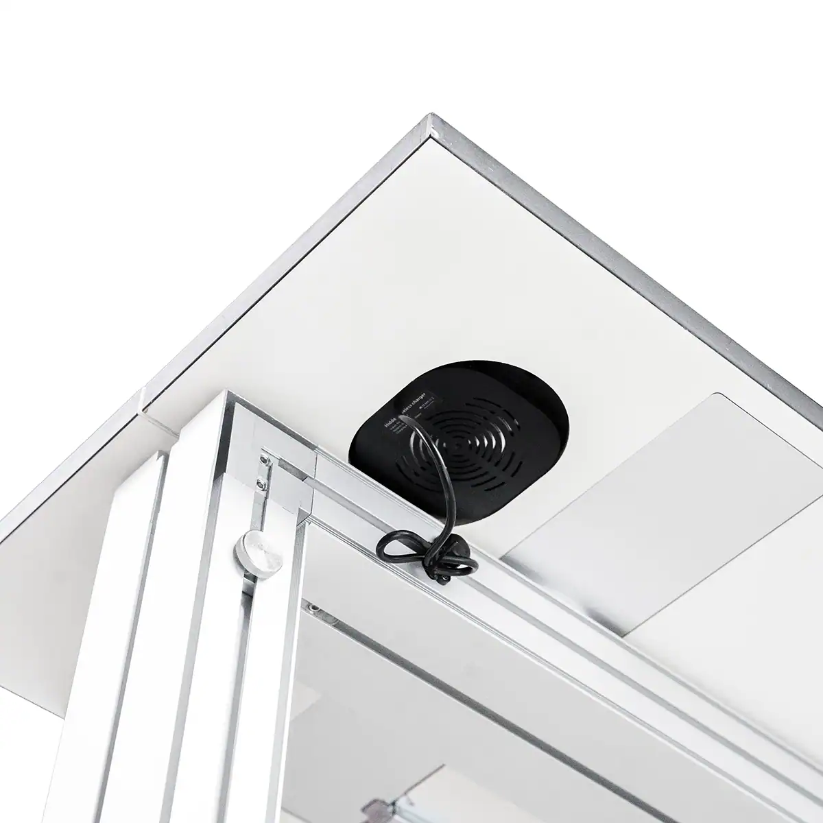 Beursstand Close-up van een zwarte ronde ventilator met een netsnoer, gemonteerd op het witte plafondpaneel in de glazen vitrine Portable RGB balie - Lumina 100x100cm.